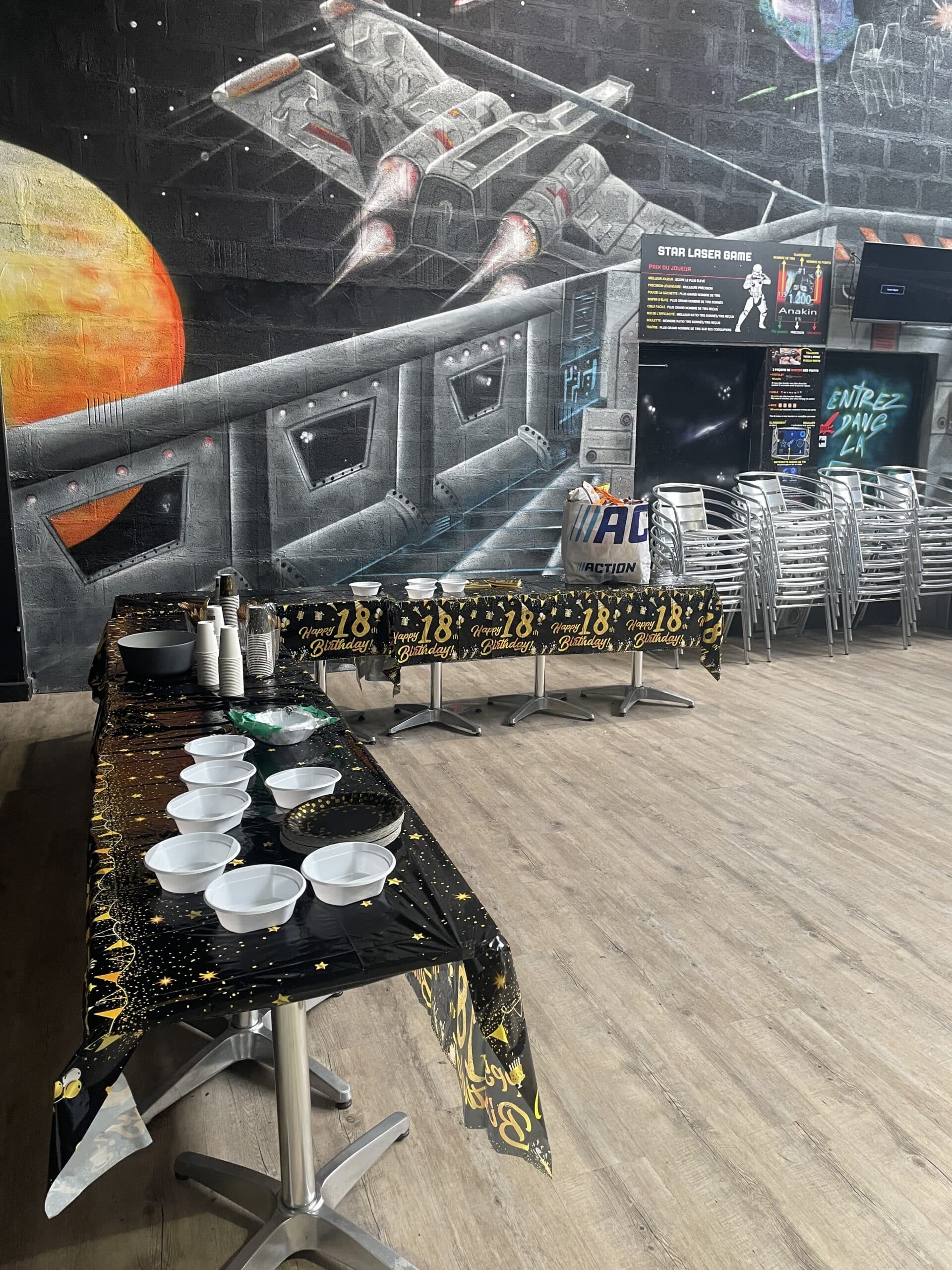 Décoration d'un 18ème anniversaire au Star Laser Game avec nappe étoilée, vaisselle jetable et fresque murale spatiale.