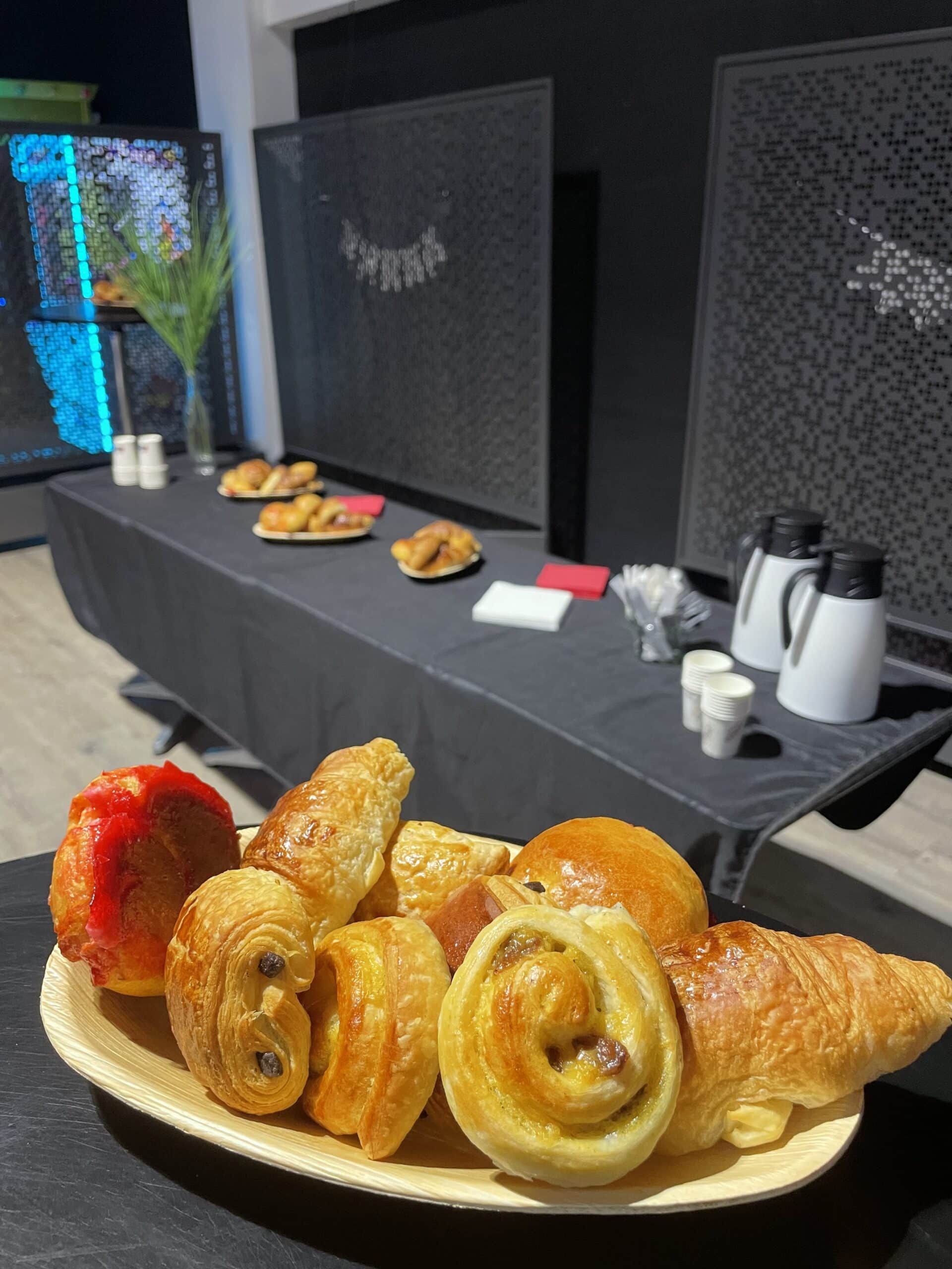 Corbeille de croissants et pains au chocolat frais lors d'un buffet petit-déjeuner pour événement professionnel.