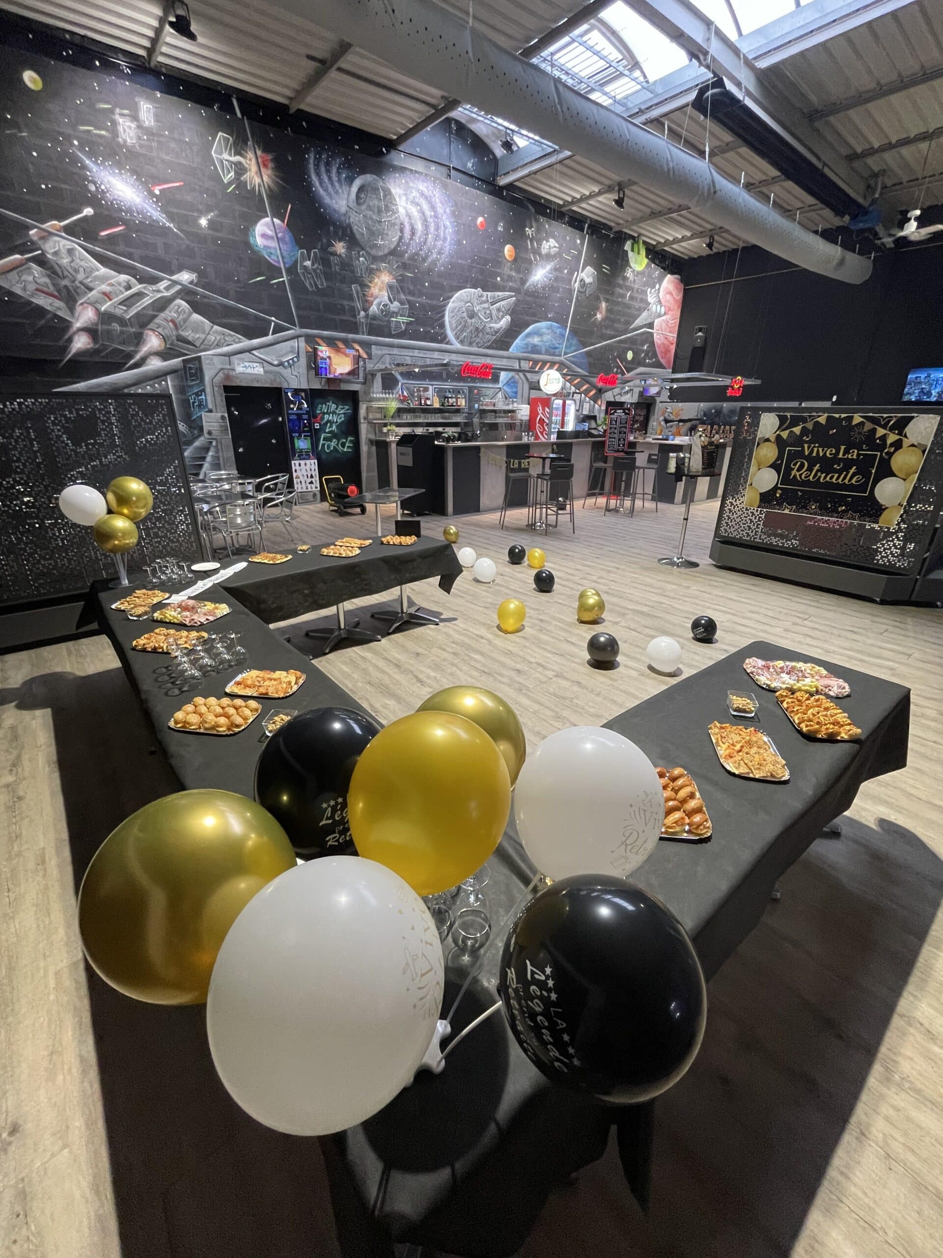 Buffet de départ en retraite avec ballons et buffet gourmand devant une fresque Star Wars géante "Vive la Retraite".