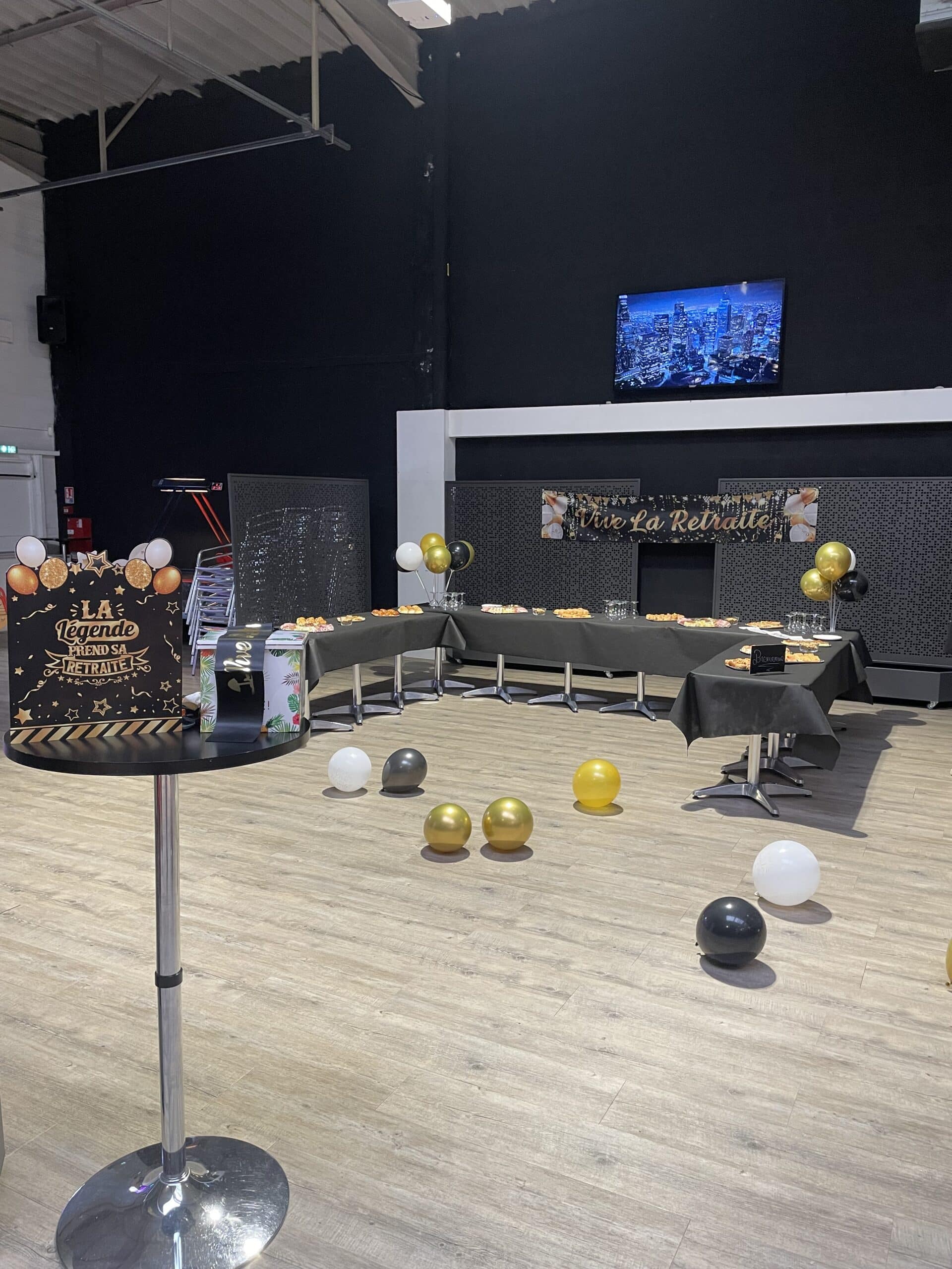 Décoration de fête de retraite avec buffet, ballons or et noirs, et affiche 'La légende prend sa retraite'.