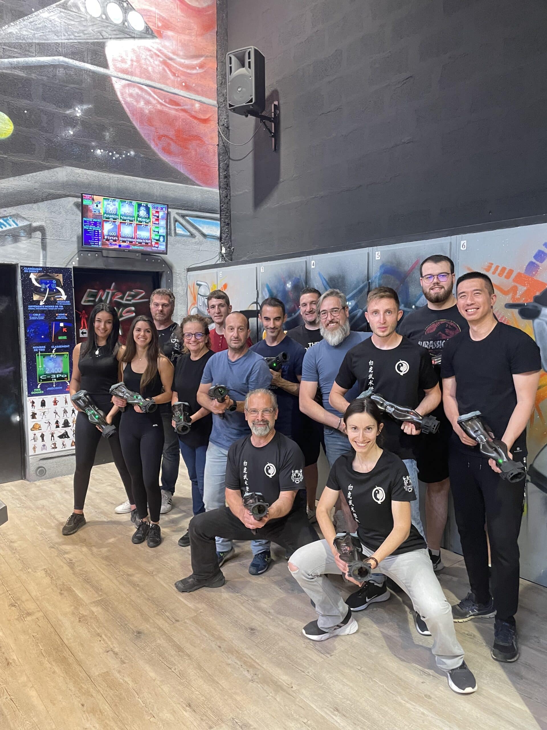 Groupe souriant avec pistolets laser tag dans une salle futuriste. Activité de loisir conviviale en intérieur.