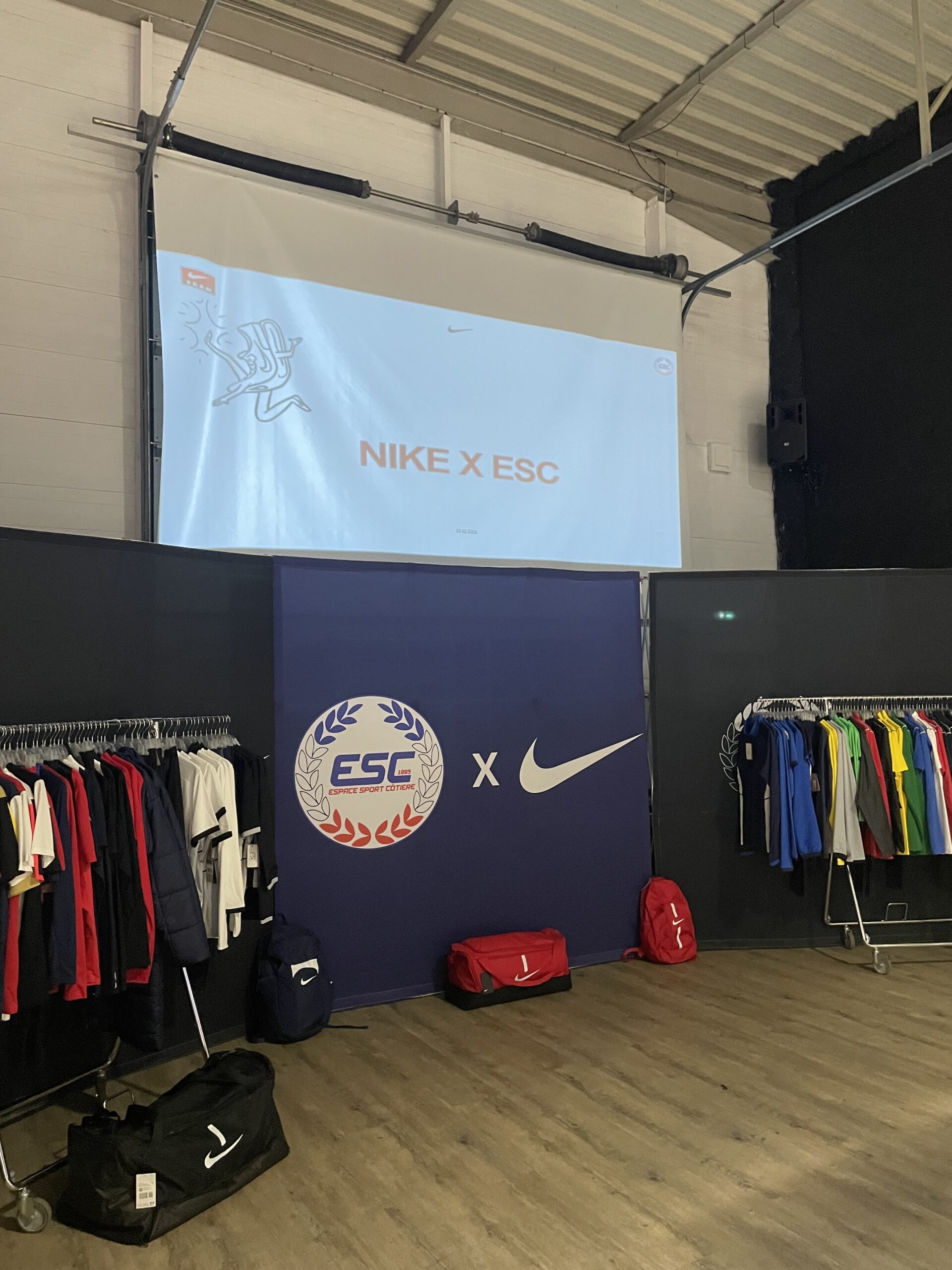 Collaboration Nike x Espace Sport Côtière (ESC) avec vêtements de sport et sacs Nike en exposition.