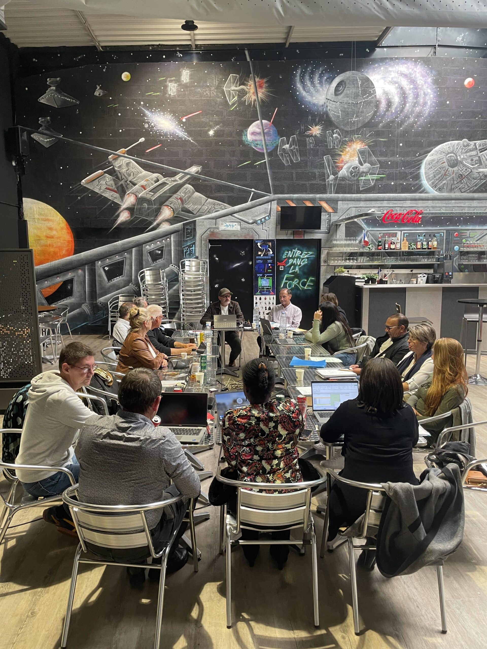 Réunion d'équipe devant une fresque Star Wars avec le message Entrez dans la Force, ambiance créative et collaborative.