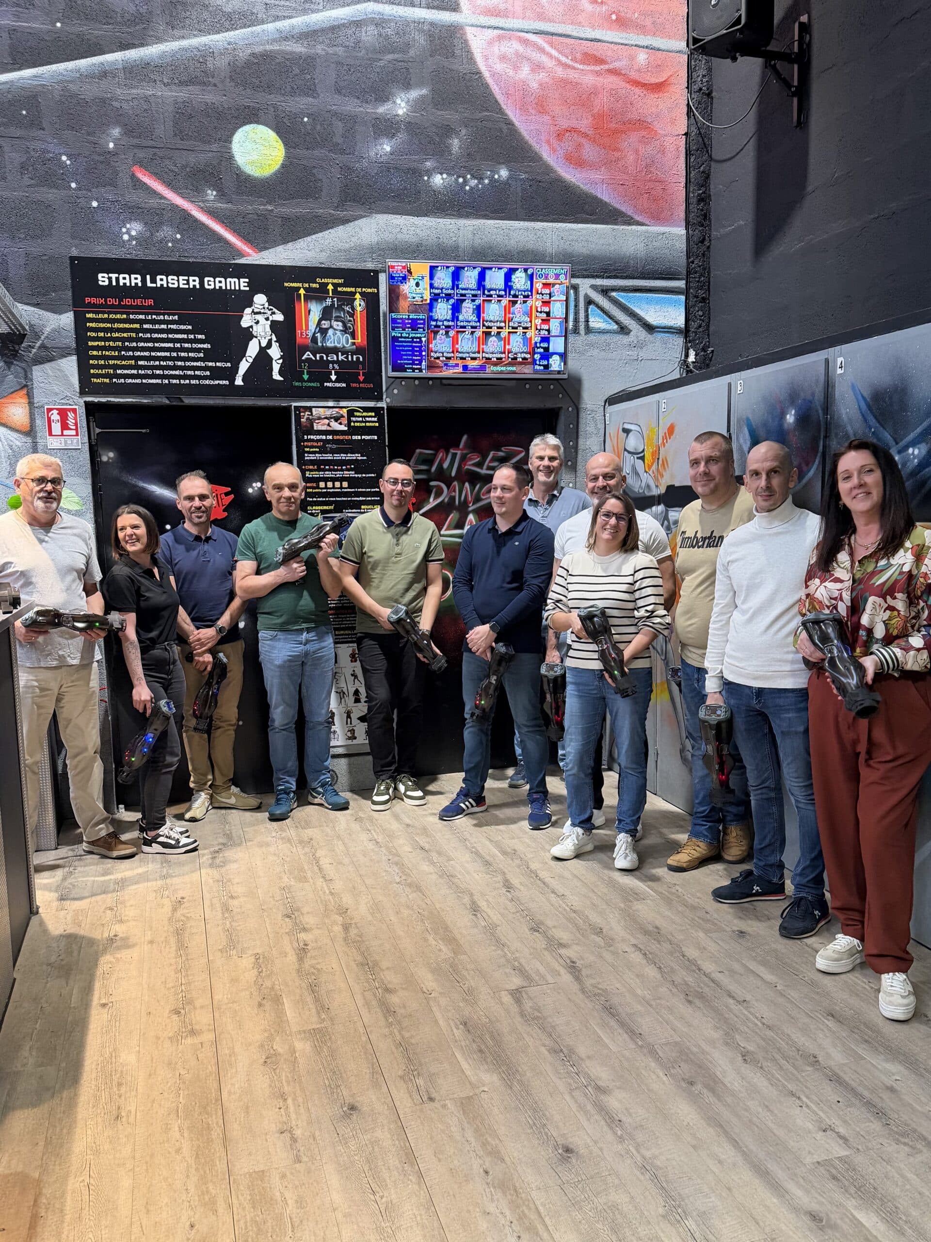 Groupe souriant avec pistolets au Star Laser Game devant un décor Star Wars et tableau de score Anakin.