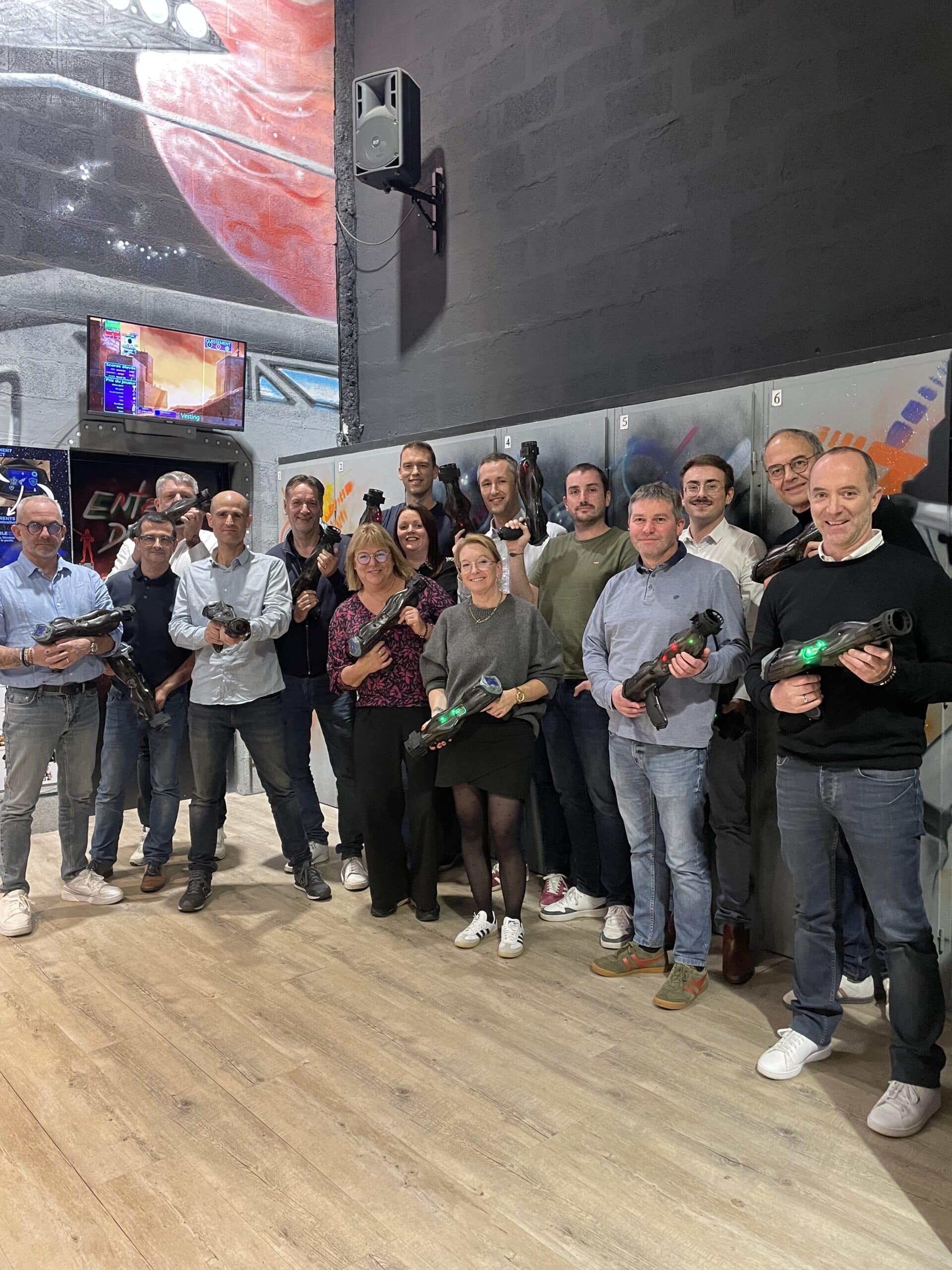 Groupe souriant avec pistolets laser tag lors d'une session de team building d'entreprise.