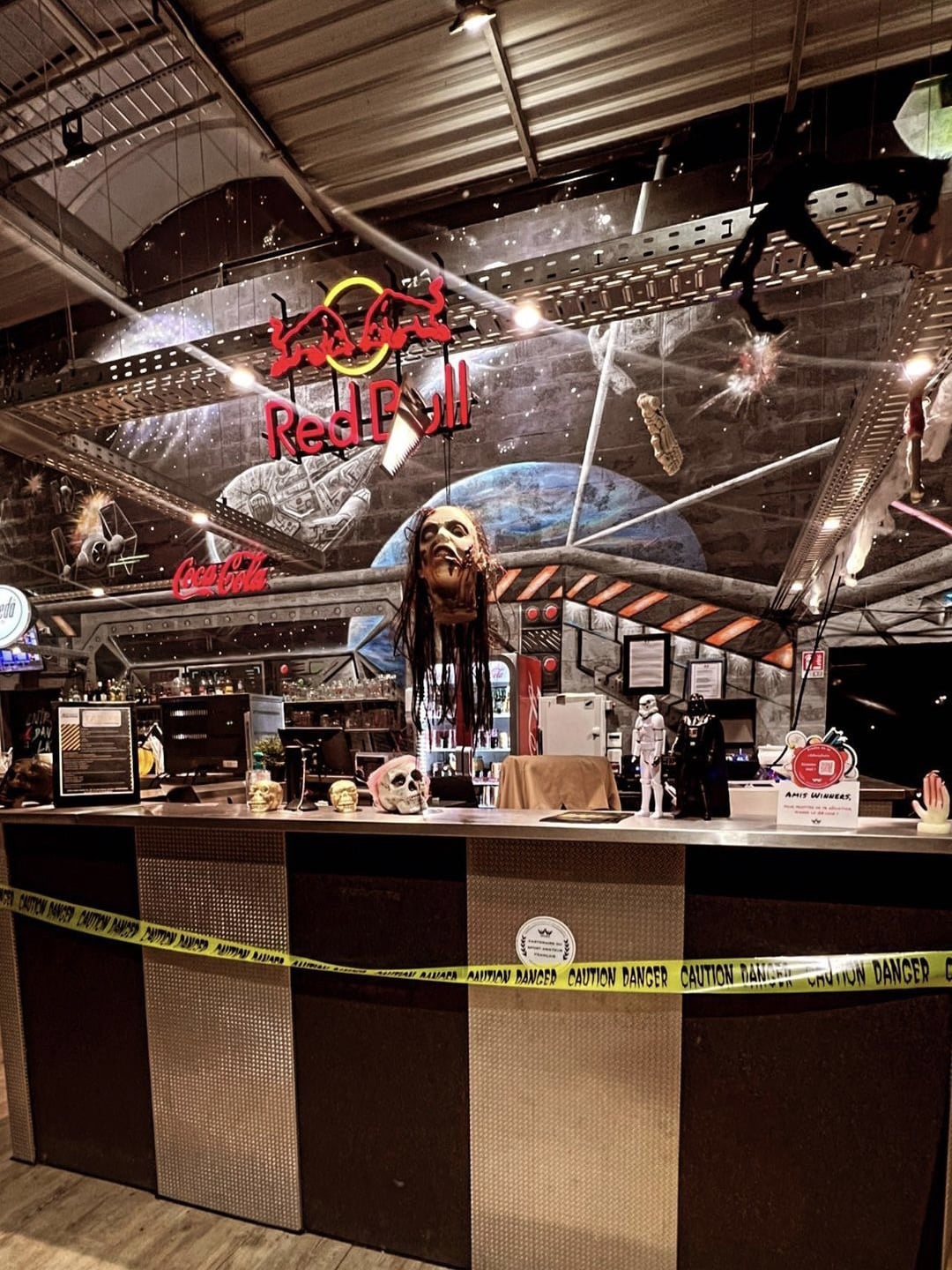 Bar à thème Star Wars et Halloween : tête coupée, crânes, néons Red Bull et ruban de sécurité Caution Danger.