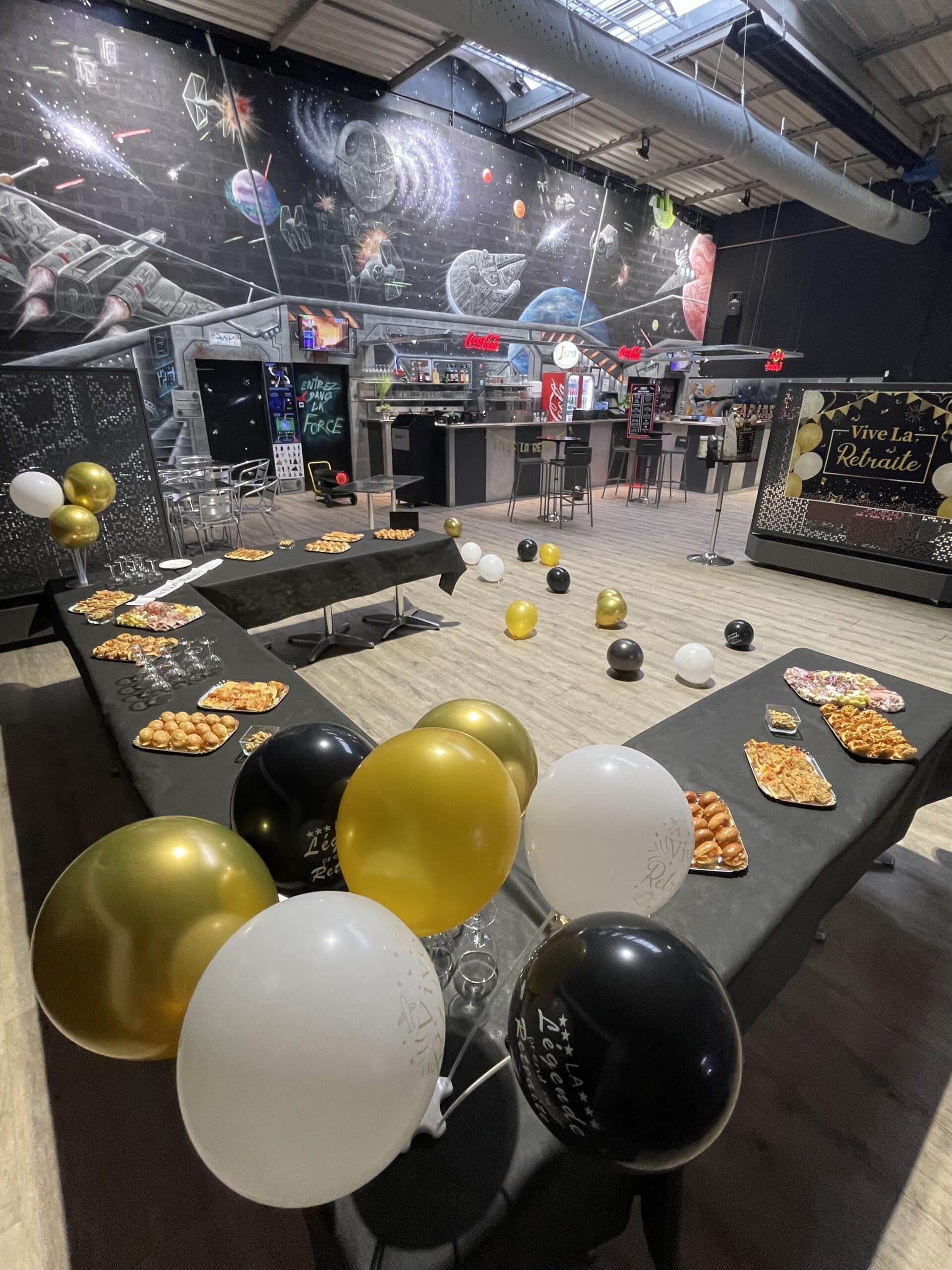 Buffet de retraite avec ballons, pancarte Vive La Retraite et fresque Star Wars décorée de vaisseaux spatiaux.