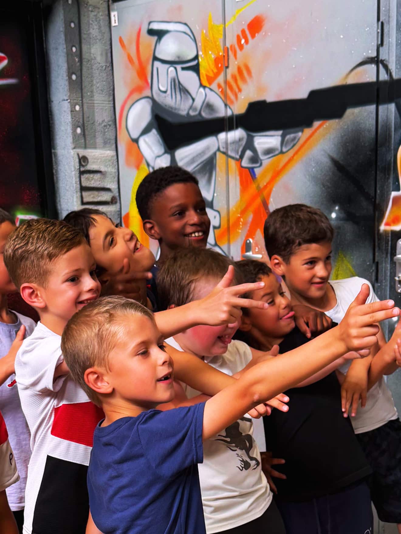Enfants souriants pointant du doigt devant un graffiti Clone Trooper. Ambiance de fête et camaraderie.