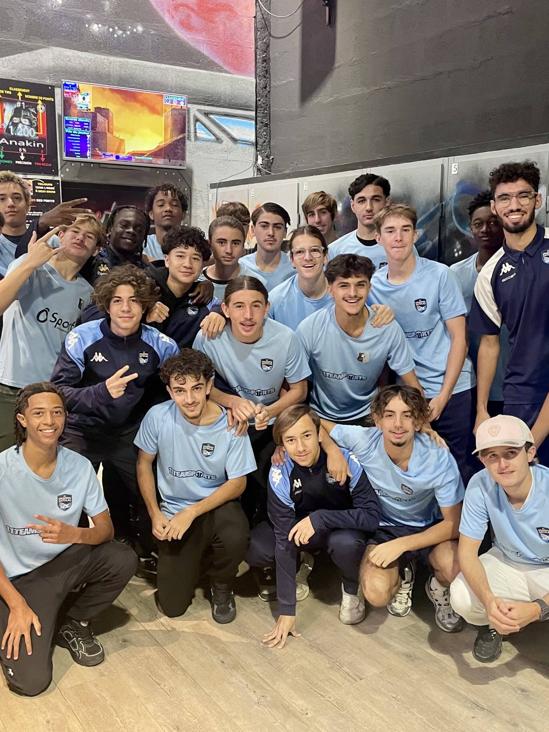 Groupe de jeunes sportifs du FC Colombier Satolas en maillots bleus posant dans un centre de loisirs et jeux.