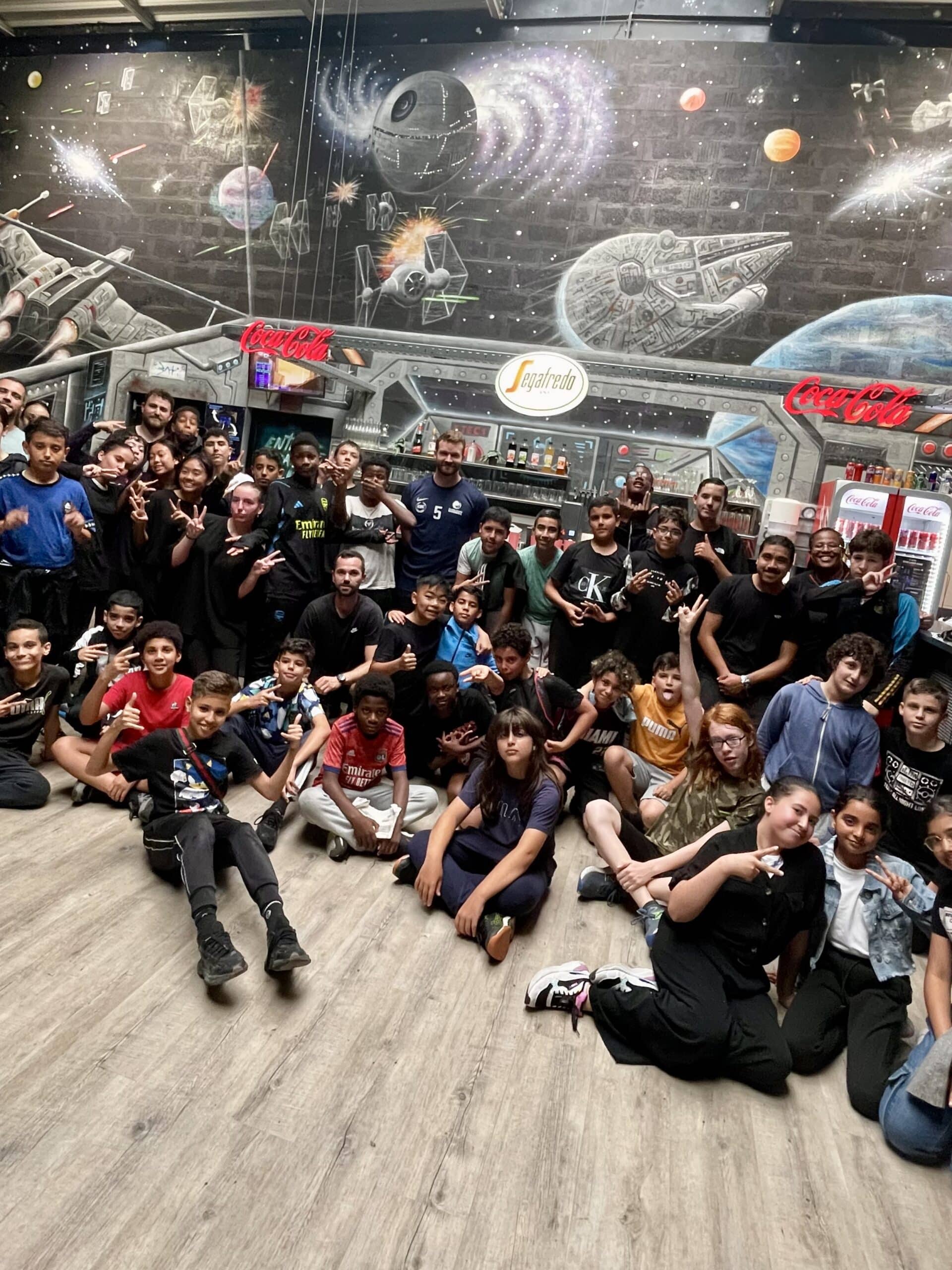 Groupe de jeunes posant joyeusement devant une fresque Star Wars avec logos Coca-Cola et Segafredo.