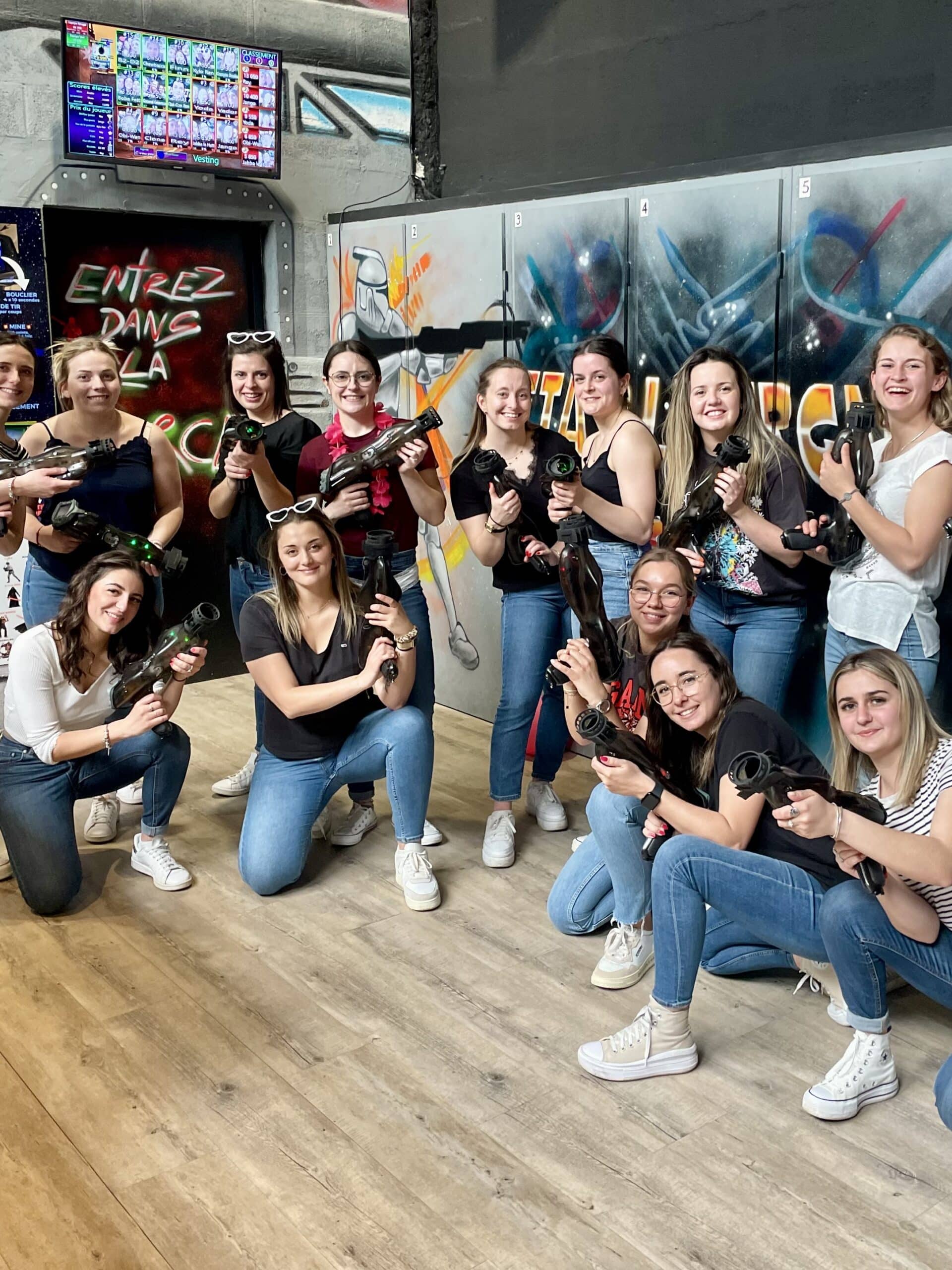 Groupe de femmes souriantes avec pistolets laser tag devant un décor Star Wars et l'enseigne Entrez dans la zone.