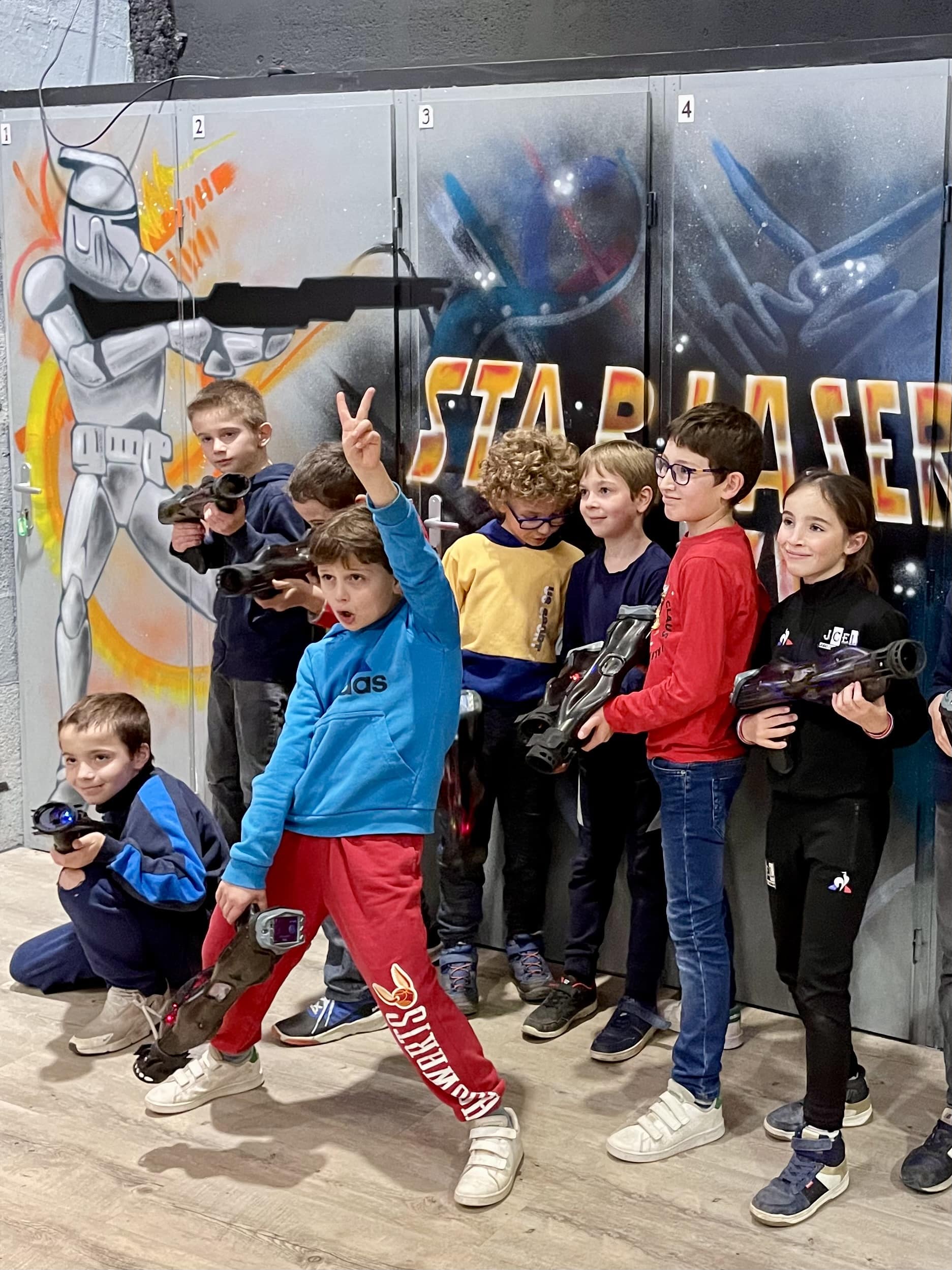 Enfants avec pistolets laser tag devant un mur Stormtrooper chez STARLASER. Action et plaisir en groupe.