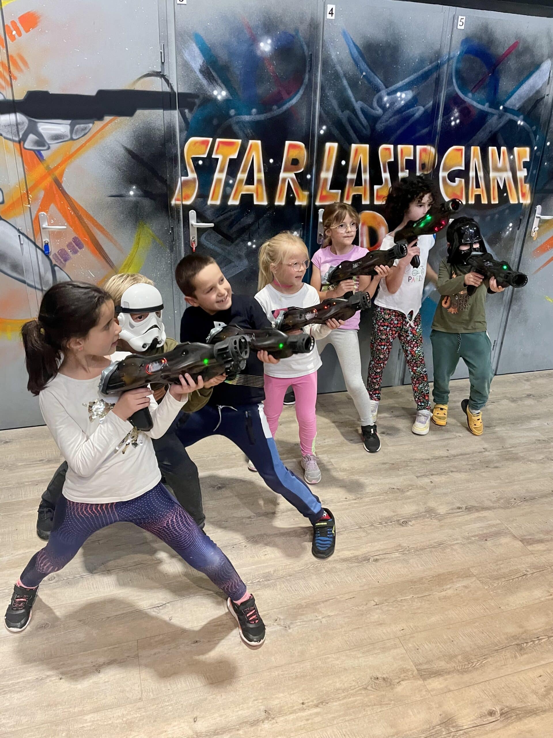 Groupe d'enfants en pleine action au Star Laser Game avec blasters et masques Star Wars, ambiance ludique et dynamique.