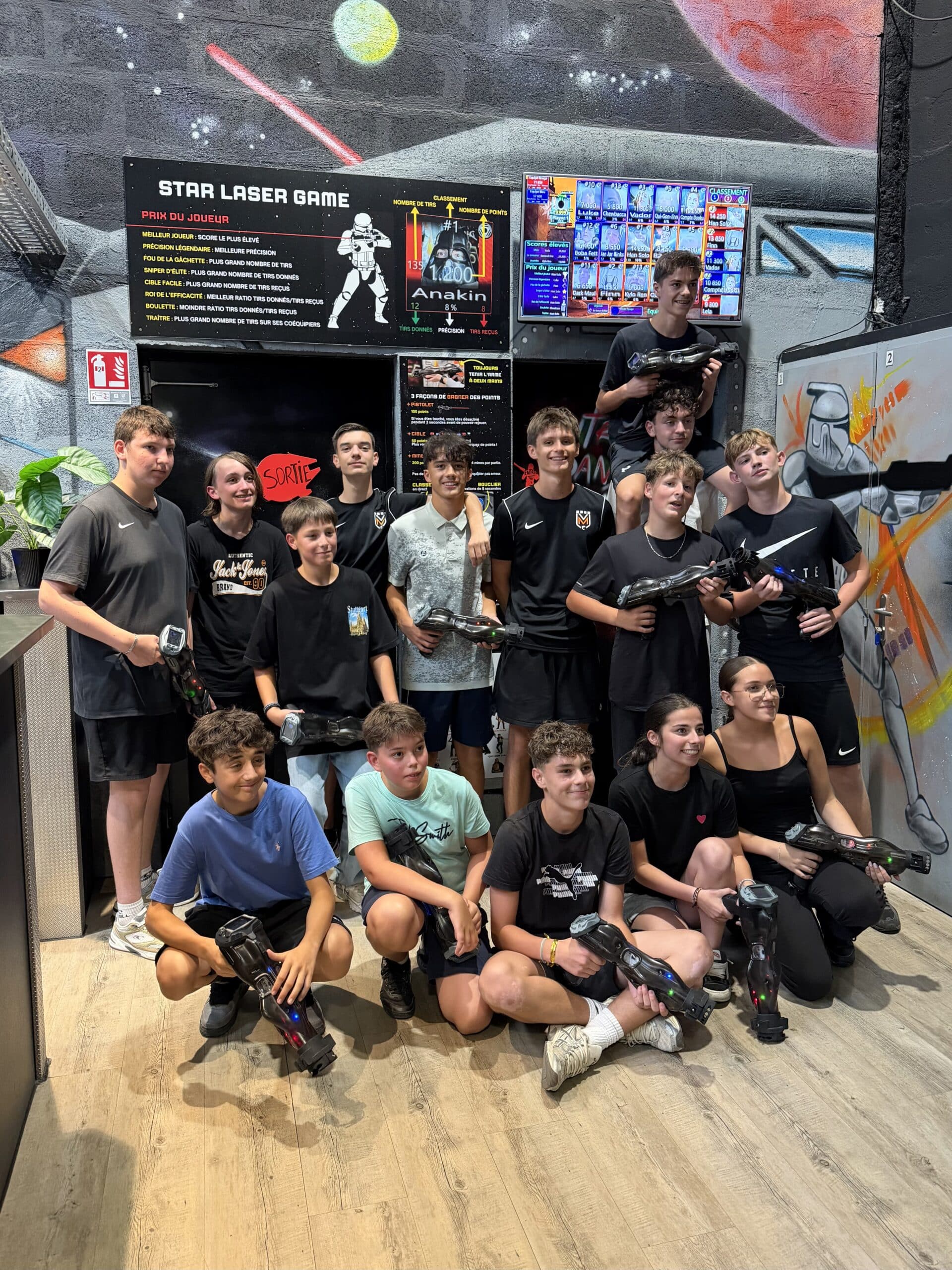 Groupe d'adolescents souriants posant avec des pistolets laser tag dans un centre Star Laser Game.